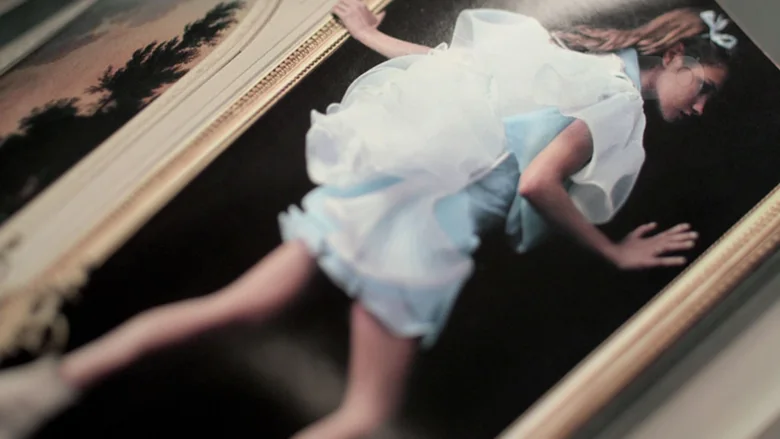 A magazine spread of a figure in a pale blue dress beside a gilt frame