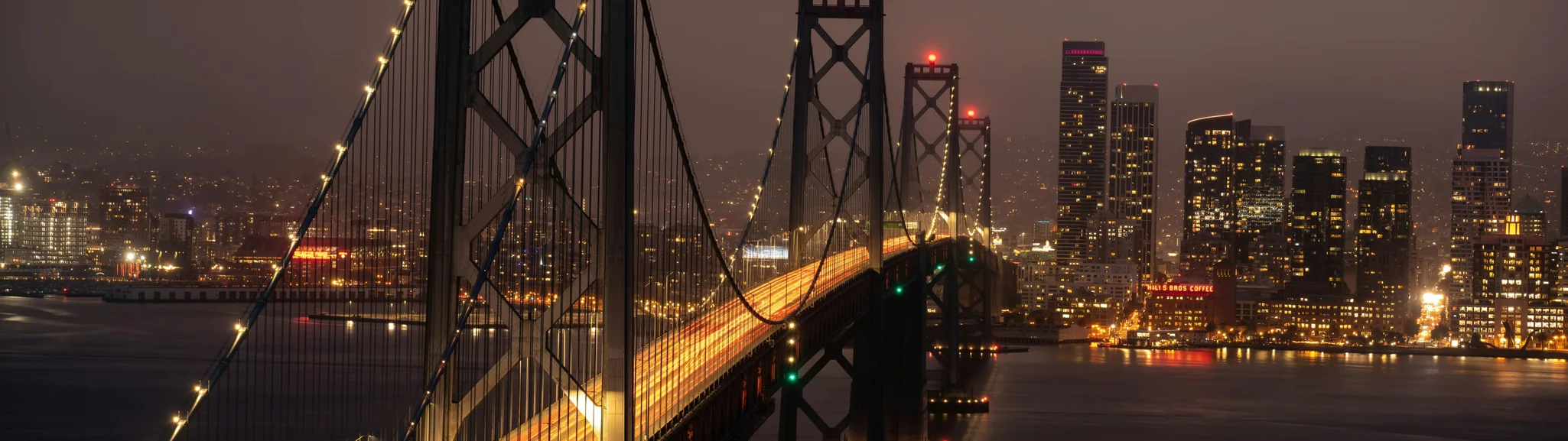 The Bay Bridge lit at night against the San Francisco skyline