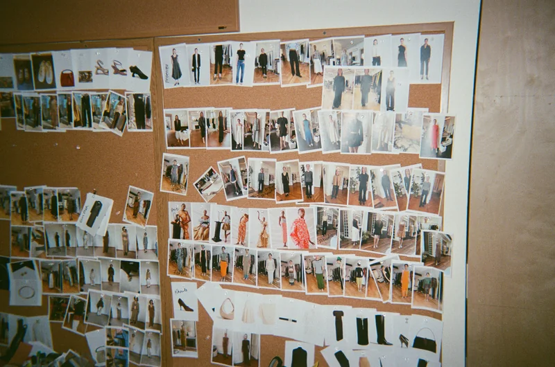 A cork board densely pinned with fashion line-sheet photographs